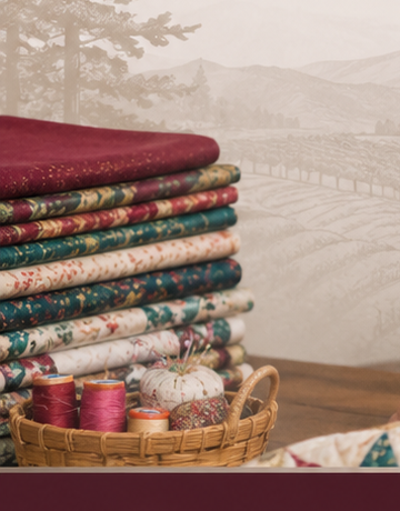 Stack of folded fabric bolts beside a basket of thread spools in a Sebastopol quilting studio